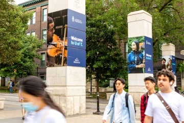 student walk past the front gate of the Ƶ